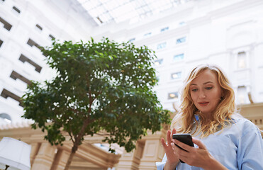 Image showing Businesswoman using smartphone in the modern bank lobby