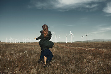 Image showing Woman with long tousled hair next to the wind turbine with the w