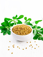 Image showing Fenugreek with green leaves in bowl on light wooden board