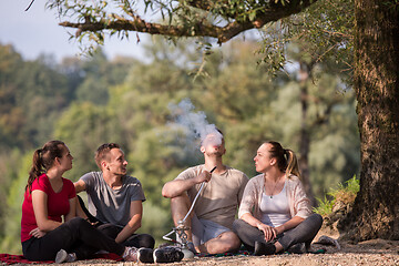 Image showing friends smoking hookah on the river bank