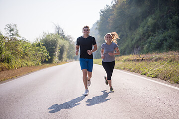 Image showing young couple jogging along a country road