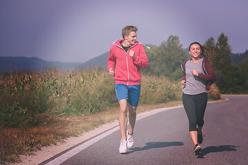 Image showing young couple jogging along a country road