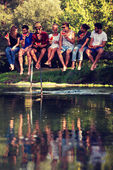 Image showing friends enjoying watermelon while sitting on the wooden bridge