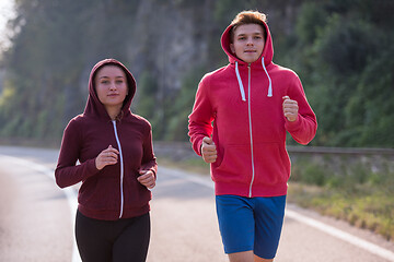 Image showing young couple jogging along a country road