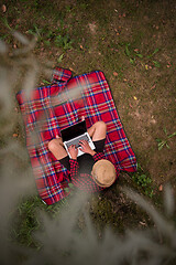 Image showing top view of man using a laptop computer under the tree