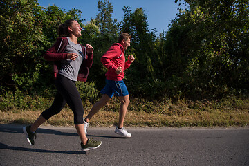 Image showing young couple jogging along a country road