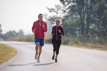 Image showing young couple jogging along a country road