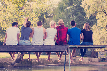 Image showing rear view of friends enjoying watermelon while sitting on the wo