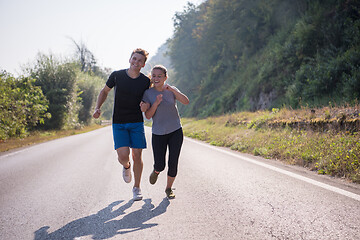 Image showing young couple jogging along a country road