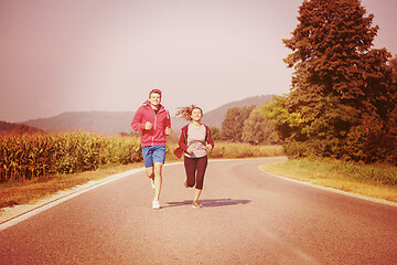 Image showing young couple jogging along a country road