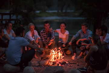 Image showing young friends relaxing around campfire