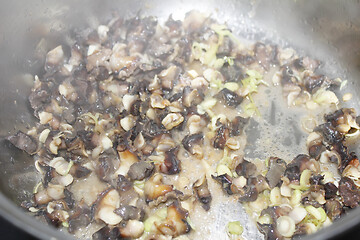 Image showing Closeup of eating the fried snails with stalks lemon grass 