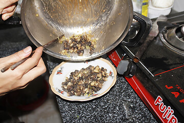 Image showing Closeup of eating the fried snails with stalks lemon grass 