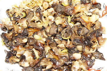 Image showing Closeup of eating the fried snails with stalks lemon grass 