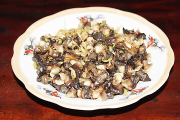 Image showing Closeup of eating the fried snails with stalks lemon grass 