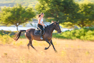 Image showing Girl rides a horse across the field