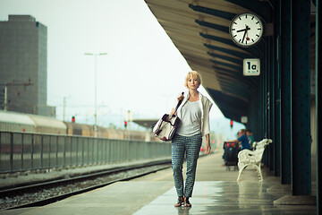 Image showing Blonde caucasian woman waiting at the railway station carrying bag