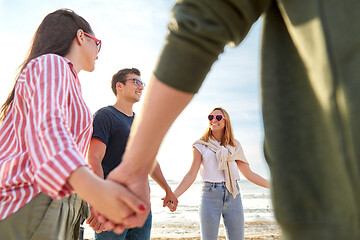 Image showing happy friends holding hands on summer beach