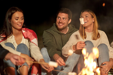 Image showing friends roasting marshmallow on camp fire at night