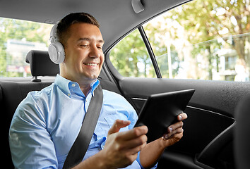 Image showing passenger with headphones using tablet pc in car