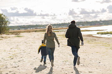 Image showing happy family running along autumn beach