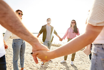 Image showing happy friends holding hands on summer beach