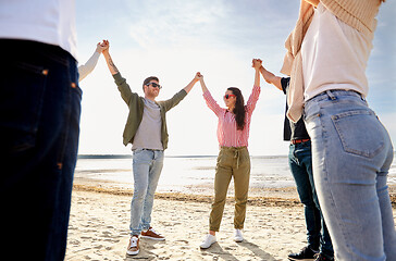 Image showing happy friends holding hands on summer beach