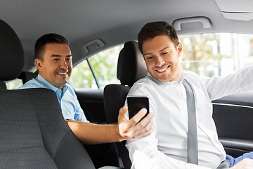 Image showing male passenger showing smartphone to car driver