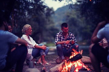 Image showing young friends relaxing around campfire