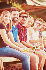 Image showing friends enjoying watermelon while sitting on the wooden bridge