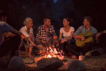 Image showing young friends relaxing around campfire