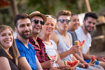 Image showing friends enjoying watermelon while sitting on the wooden bridge