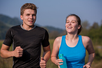 Image showing young couple jogging along a country road