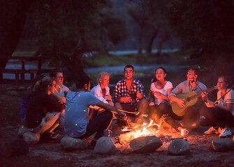 Image showing young friends relaxing around campfire