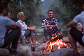 Image showing young friends relaxing around campfire