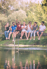 Image showing friends enjoying watermelon while sitting on the wooden bridge