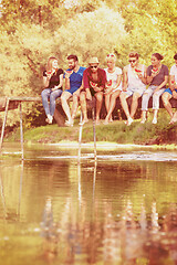 Image showing friends enjoying watermelon while sitting on the wooden bridge