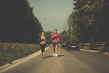 Image showing young couple jogging along a country road