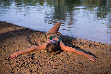 Image showing girl in a green bikini relaxing on the riverbank