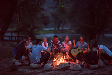 Image showing young friends relaxing around campfire