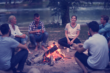 Image showing young friends relaxing around campfire