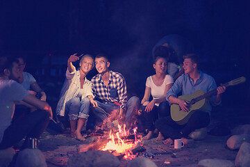 Image showing young friends relaxing around campfire