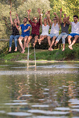 Image showing friends enjoying watermelon while sitting on the wooden bridge