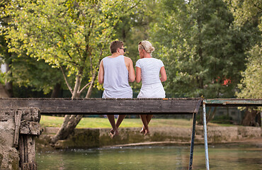 Image showing couple enjoying watermelon while sitting on the wooden bridge