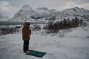 Image showing Muslim traveler praying in cold snowy winter day