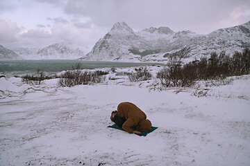 Image showing Muslim traveler praying in cold snowy winter day