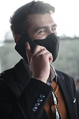 Image showing business man wearing coronavirus medical face mask while using smartphone