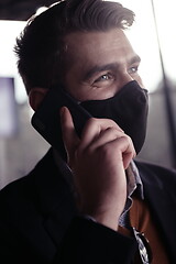 Image showing business man wearing coronavirus medical face mask while using smartphone