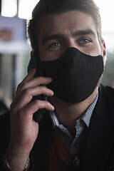 Image showing business man wearing coronavirus medical face mask while using smartphone