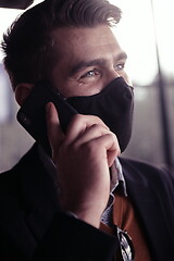 Image showing business man wearing coronavirus medical face mask while using smartphone